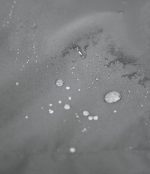Macro shot demonstrating the Leapy jacket's high-performance waterproof capability, showing water beading up and rolling off the fabric surface to keep the wearer dry during rainy hikes and wet outdoor conditions.