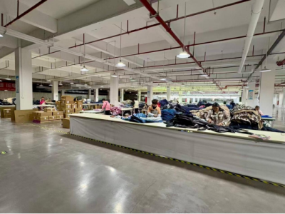 Leapy inspection workshop where workers are sorting and quality-checking finished garments on a long production table.
